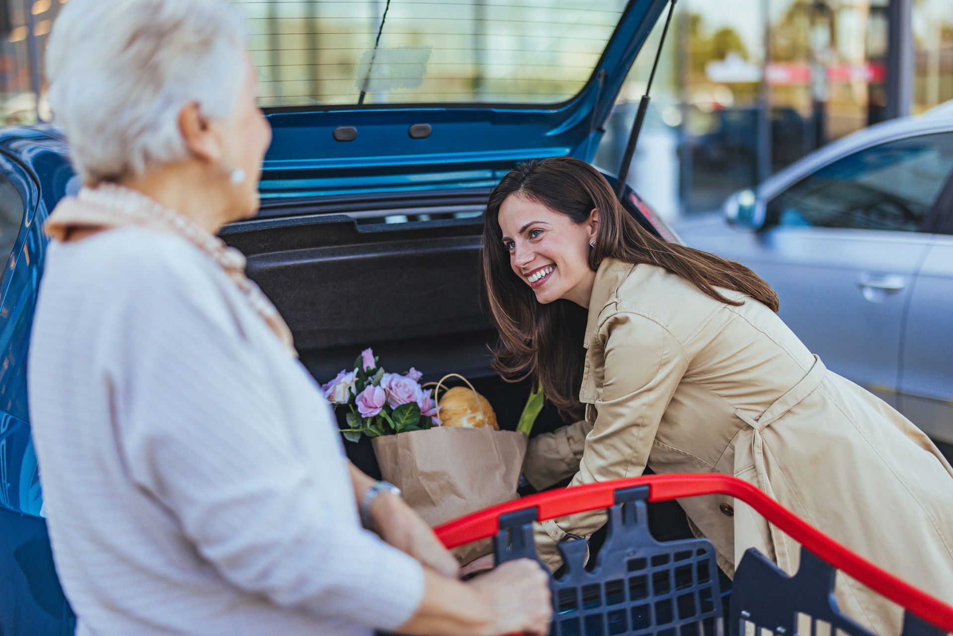 Young Woman Helps Elderly Lady With Groceries In Parking Lot
