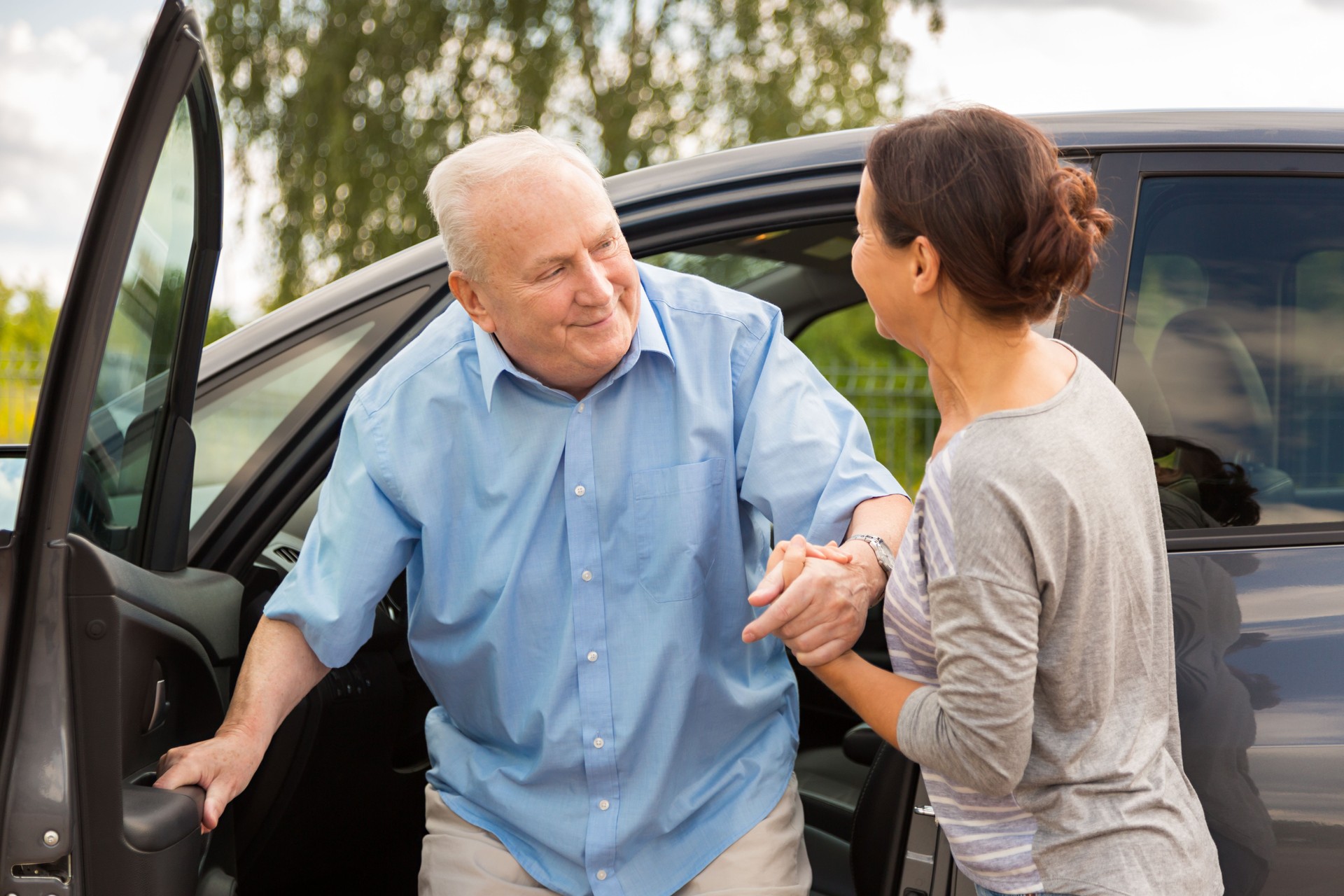 Woman helping senior out of the car