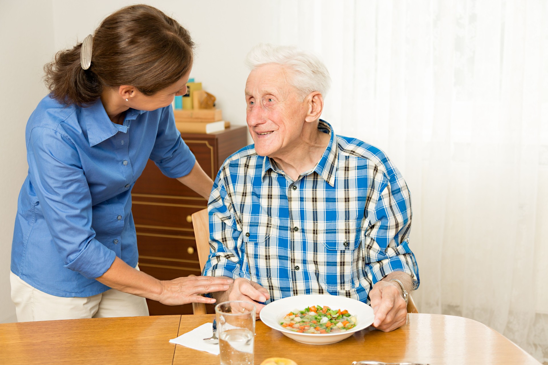 Home caregiver giving senior man lunch