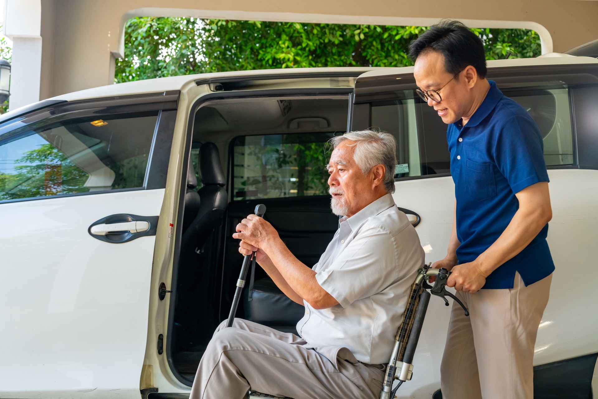 Caregiver helping senior man get in the car.